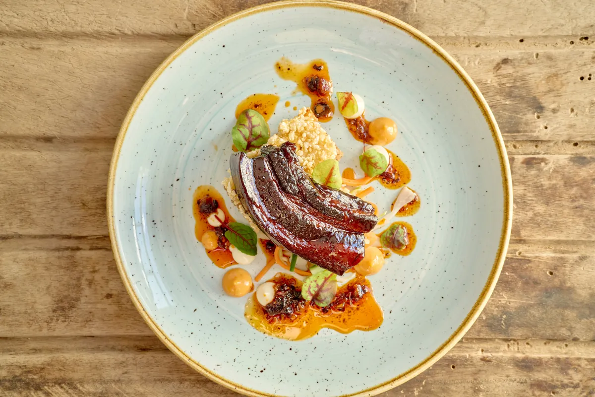 Slow soy-braised pork belly, glazed, on a speckled plate
