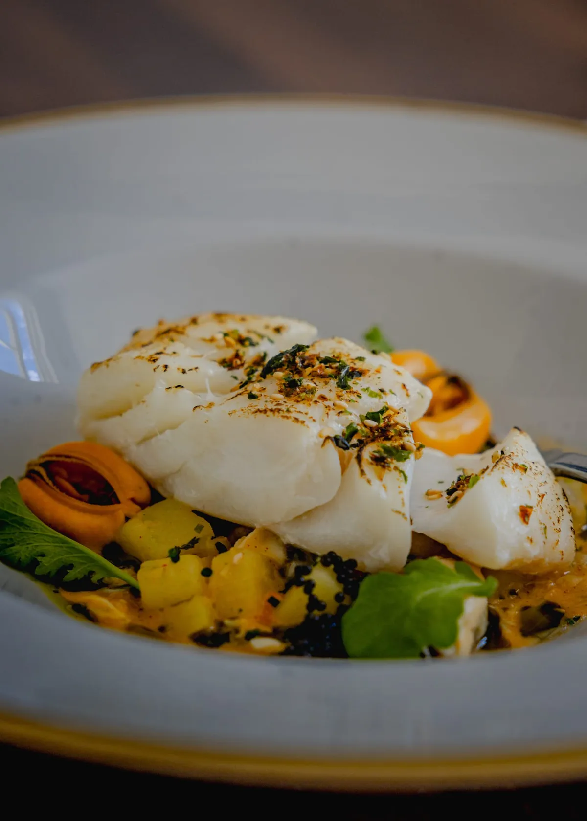 Cornish market fish, side view, on a clam and white miso chowder