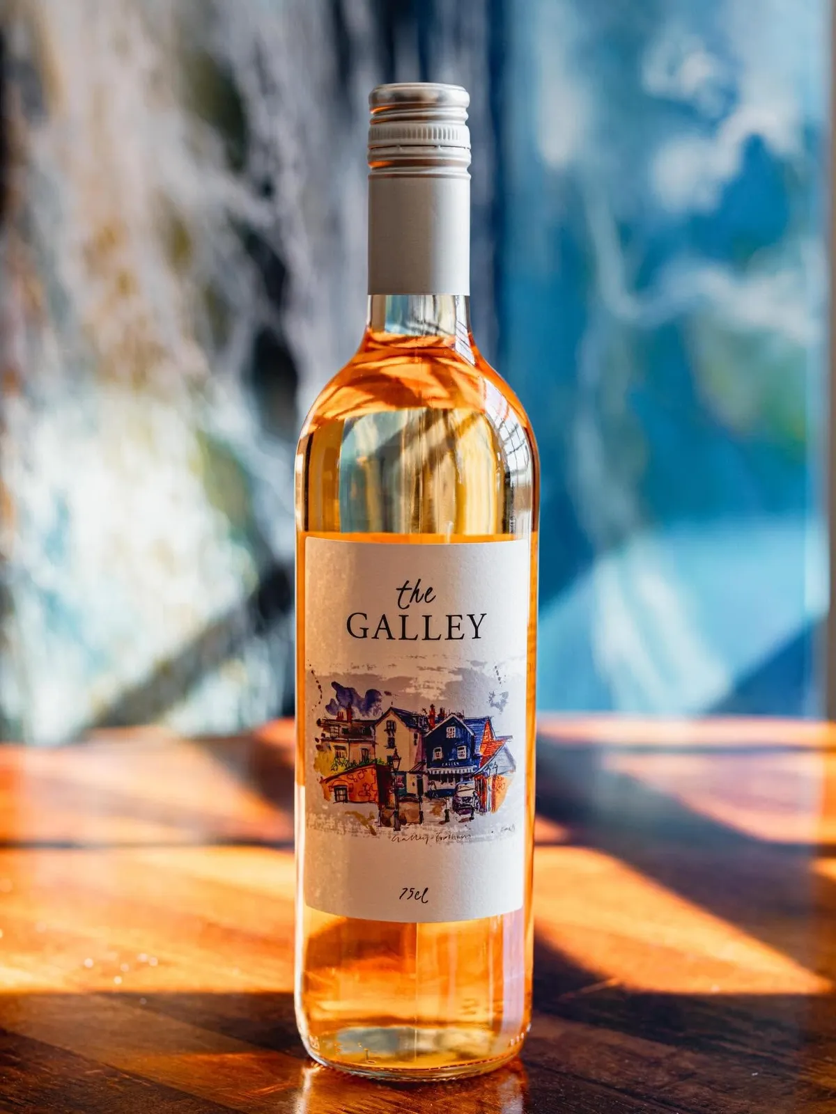 A bottle of The Galley wine on a sunlit wooden table