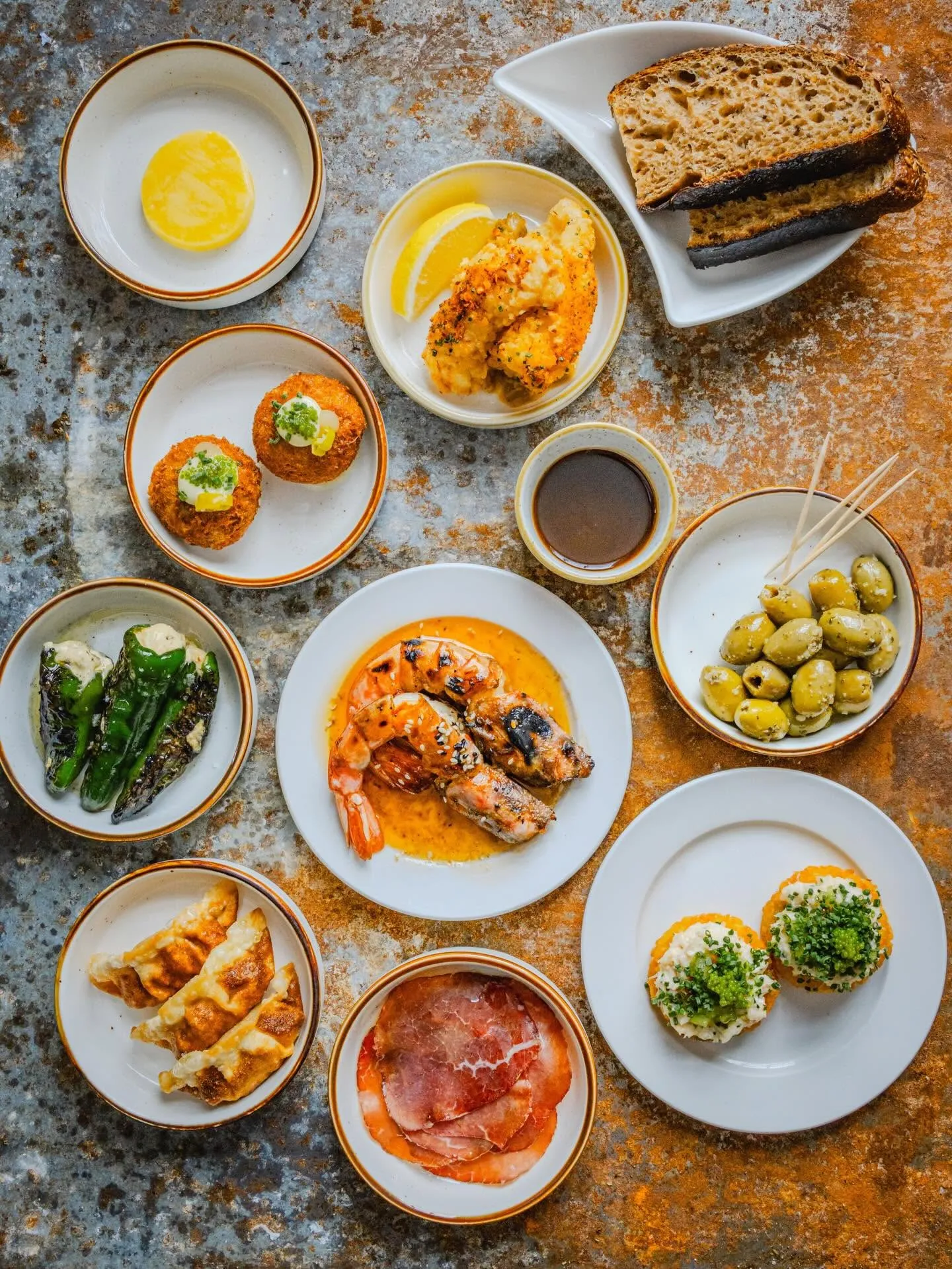 A spread of small plates at The Galley — sourdough, marinated olives, croquettes, grilled king prawns, gyoza and charcuterie